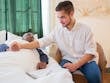A young man comforts an elderly man in bed, foster warmth and care.