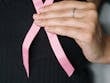 Close-up of a woman holding a pink ribbon, symbolizing breast cancer awareness.
