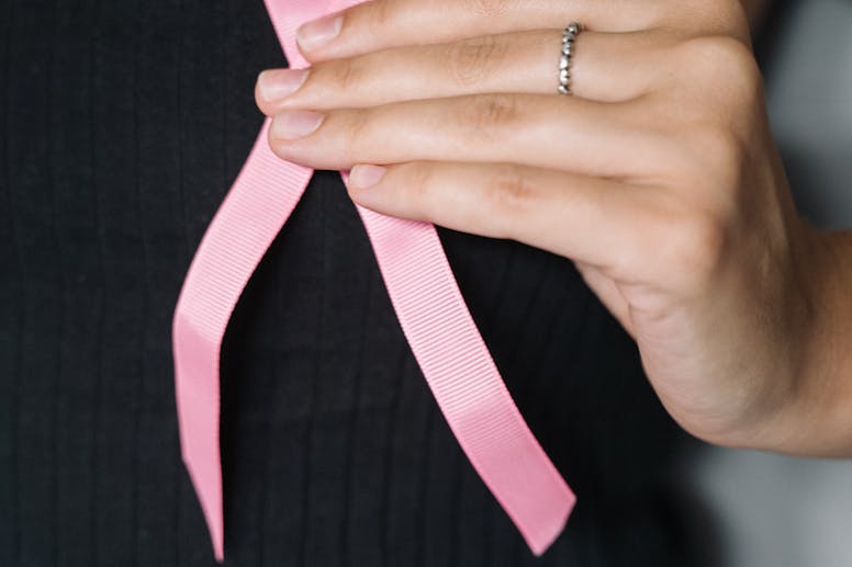 Close-up of a woman holding a pink ribbon, symbolizing breast cancer awareness.
