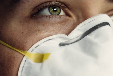 Detailed image of a person's eye and protective face mask, representing health safety.