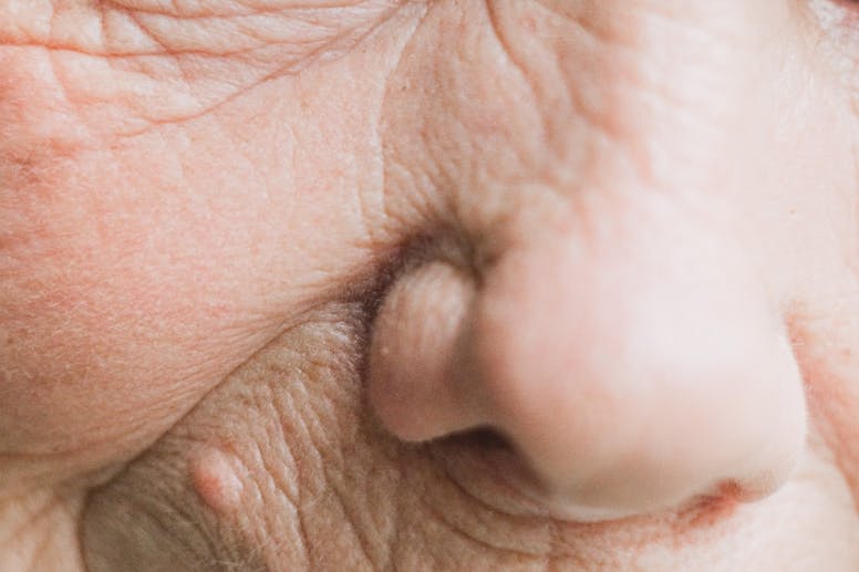 Extreme close-up of an elderly person's eye and face, emphasizing wrinkles and textures.