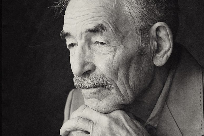 Thoughtful elderly man with cane, captured in a contemplative black and white portrait.