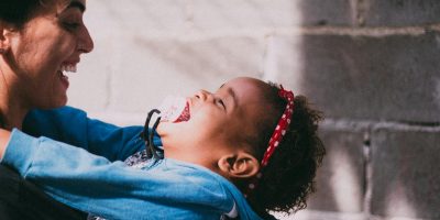 A mother and her child joyfully embrace, sharing a moment of happiness outdoors.