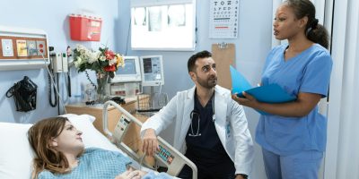 Doctors and nurse discussing patient's treatment in a hospital room.