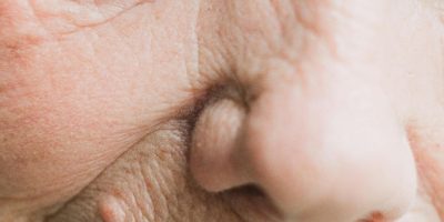 Extreme close-up of an elderly person's eye and face, emphasizing wrinkles and textures.